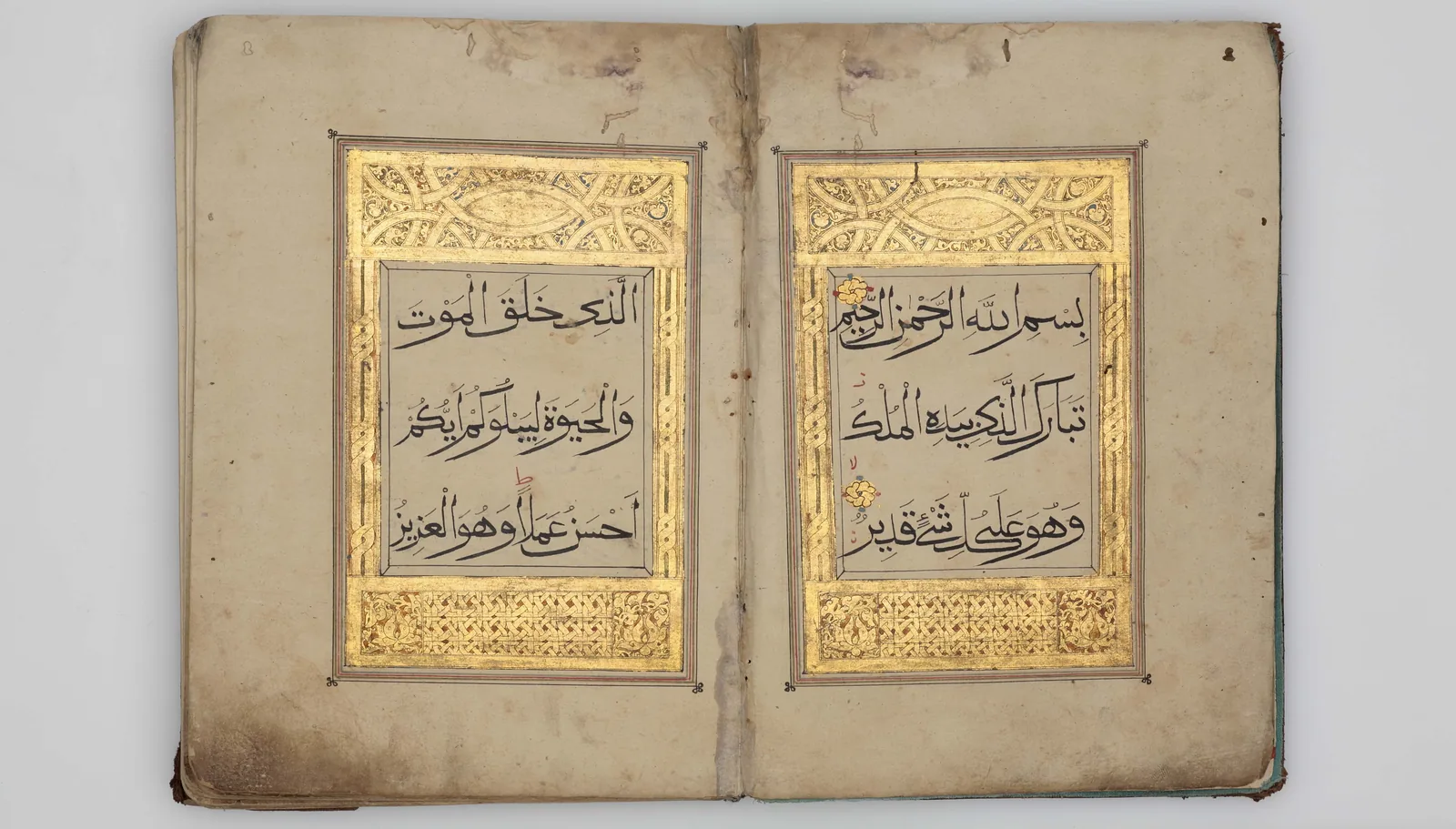 صفحتان متقابلتان من مصحفٍ مذهَّب، فيهما مطلع سورة الملك بخط المحقَّق