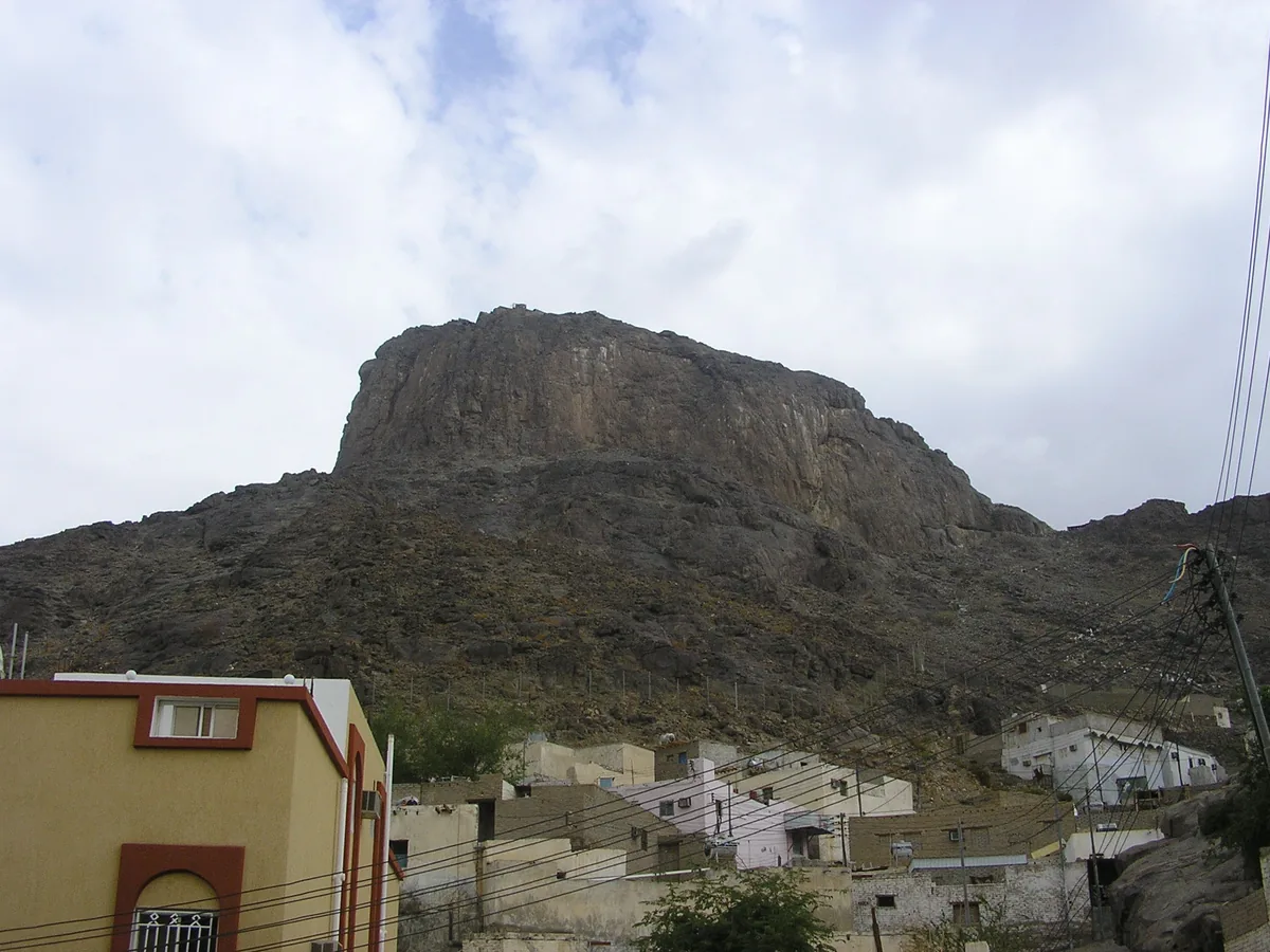 جبلٌ صخريٌّ مرتفع تحته مبانٍ متفرّقة.